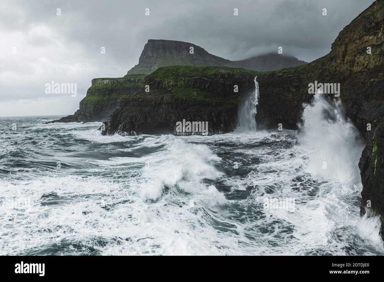 Danemark, îles Féroé, village de Gasadalur, cascade de MÂ·Lafossur, côte avec cascade de Mulafossur tombant dans l'océan Atlantique en temps de tempête Banque D'Images