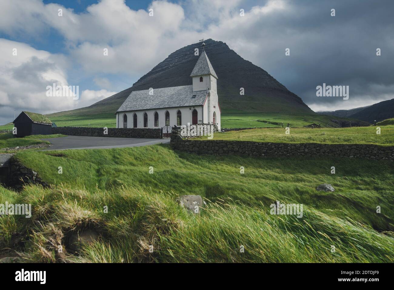 Danemark, Iles Féroé, Vidareidi, paysage vert avec église rurale et montagne Banque D'Images