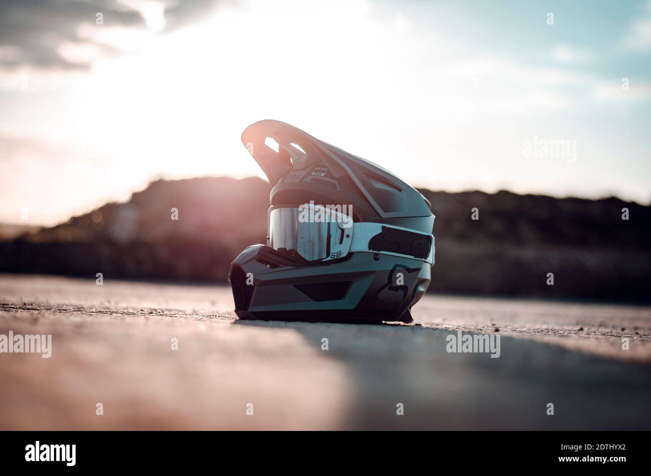 Un casque de moto repose sur le sol tandis que le soleil brille dessus. Banque D'Images