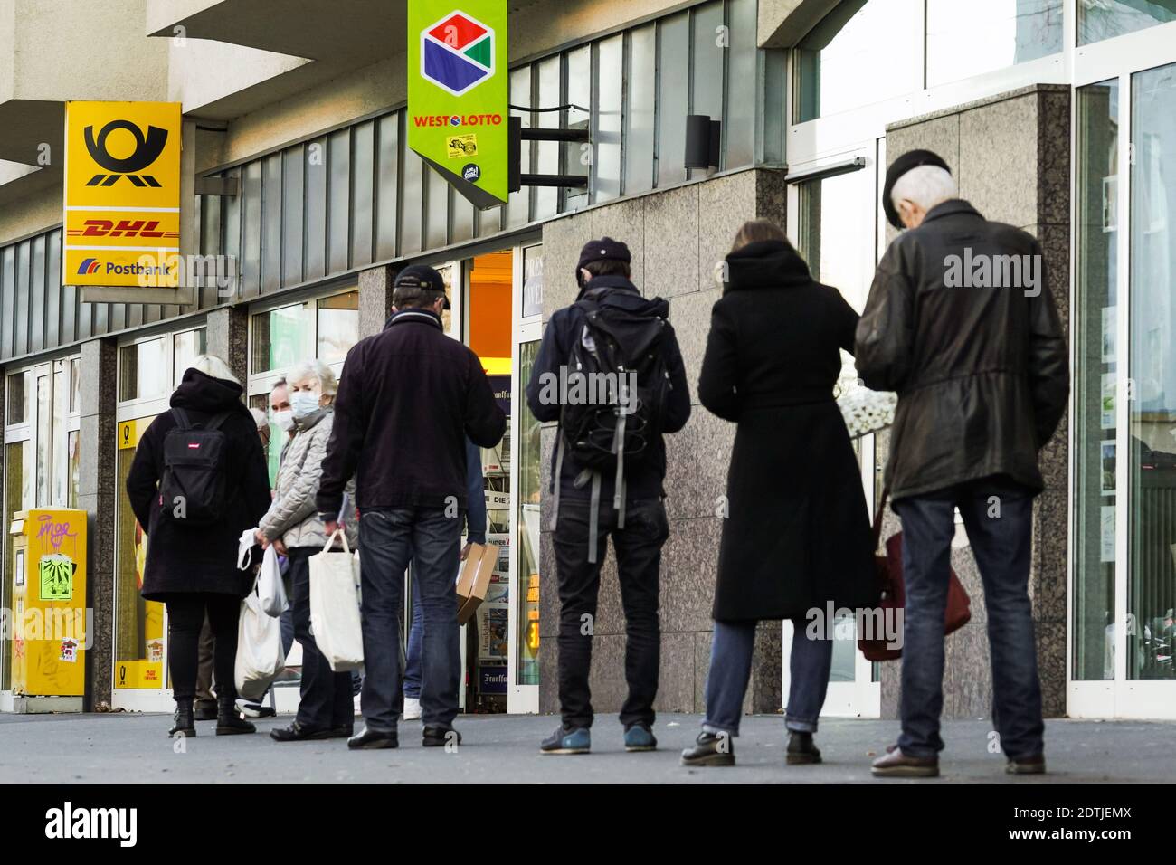 Dortmund, Allemagne, 18 décembre 2020: Les clients attendent sur le trottoir devant une succursale de Deutsche Post / DHL à Dortmund. En raison des restrictions du deuxième verrouillage de la pandémie de corona, seuls 3 clients sont autorisés à rester dans cette succursale en même temps. Banque D'Images
