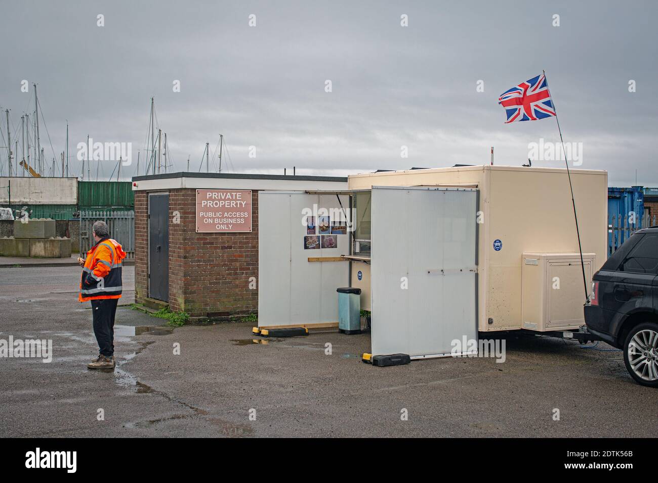 Un ouvrier du port se trouve près d'une camionnette à Brightlingsea , Essex , Angleterre Banque D'Images