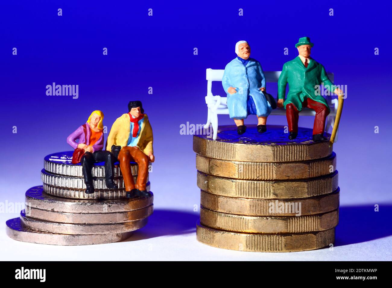 Image conceptuelle de la miniature une figure couples assis sur des pièces de monnaie isolé sur fond bleu Banque D'Images