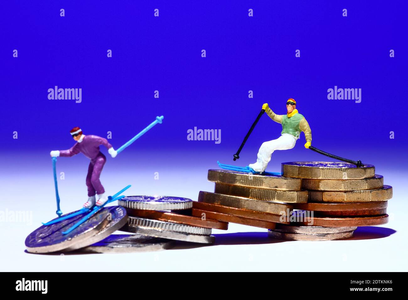 Image conceptuelle de la figure miniature des gens skiant sur une pile de pièces Banque D'Images