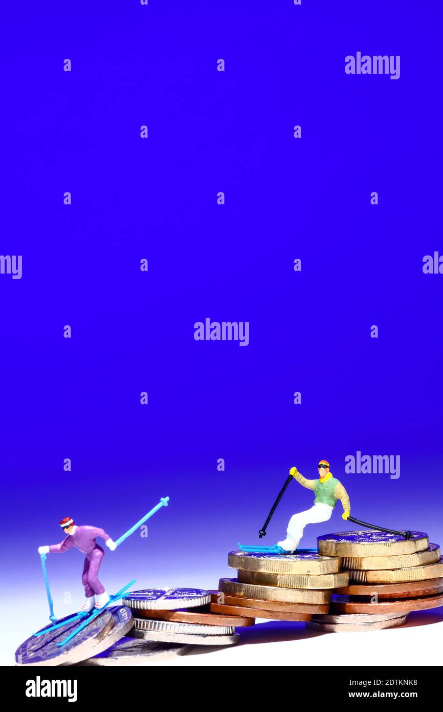 Image conceptuelle de la figure miniature des gens skiant sur une pile de pièces Banque D'Images