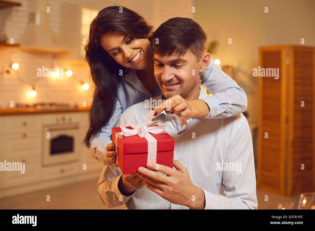 Un jeune couple souriant et aimant se serrer et déballer le cadeau de vacances pendant Fête de la Saint-Valentin Banque D'Images