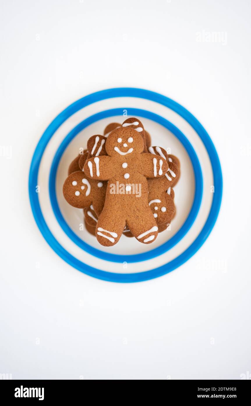 Biscuits Gingerbread Men empilés sur une assiette sur fond blanc Banque D'Images