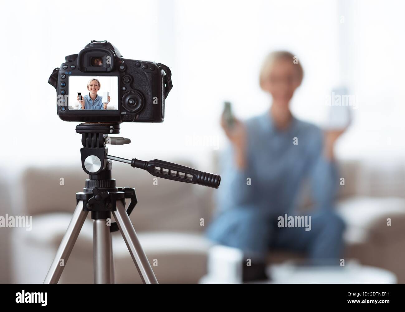 Jeune femme caucasienne enregistrant du contenu vidéo pour son blog technologique à la maison, foyer sélectif sur l'appareil photo avec écran de prévisualisation Banque D'Images