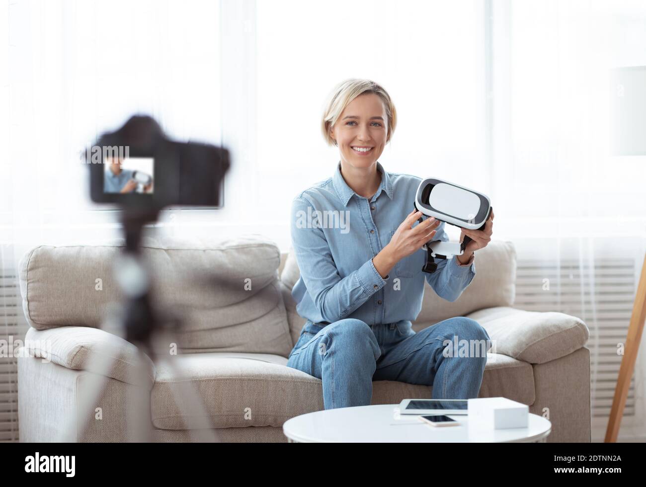 Une jeune femme vlogger tient un casque VR, montrant un appareil innovant, enregistrant une vidéo pour son blog technologique sur caméra Banque D'Images