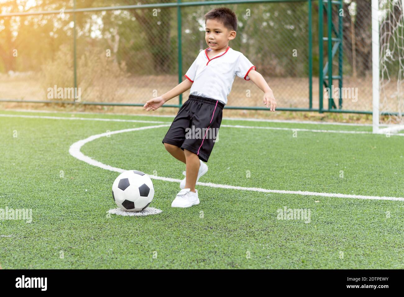 Le garçon jouait au football sur le terrain de football avec bonheur. Banque D'Images
