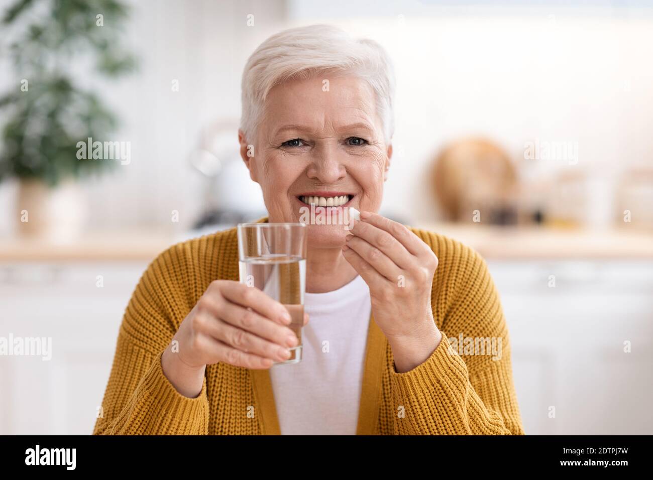 Bonne dame senior tenant un verre d'eau et de pilule Banque D'Images