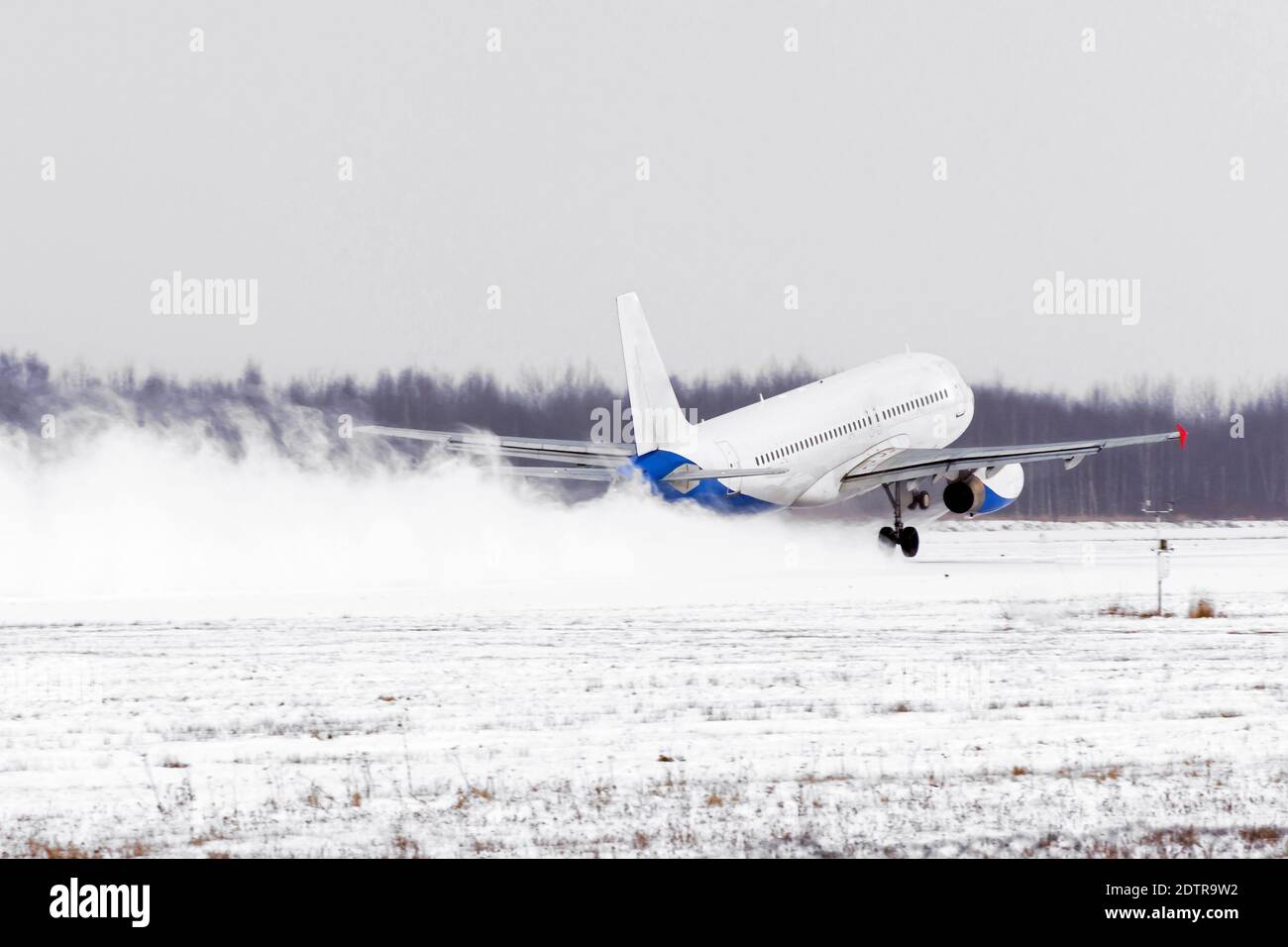 Décollage de l'avion de l'aéroport couvert de neige par mauvais temps pendant une tempête de neige, un vent fort en hiver Banque D'Images
