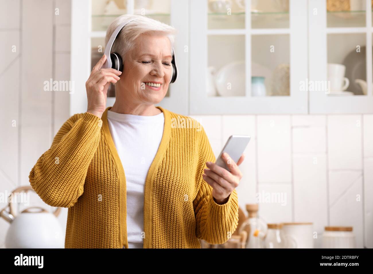 Portrait d'une femme âgée heureuse écoutant de la musique sur un smartphone Banque D'Images