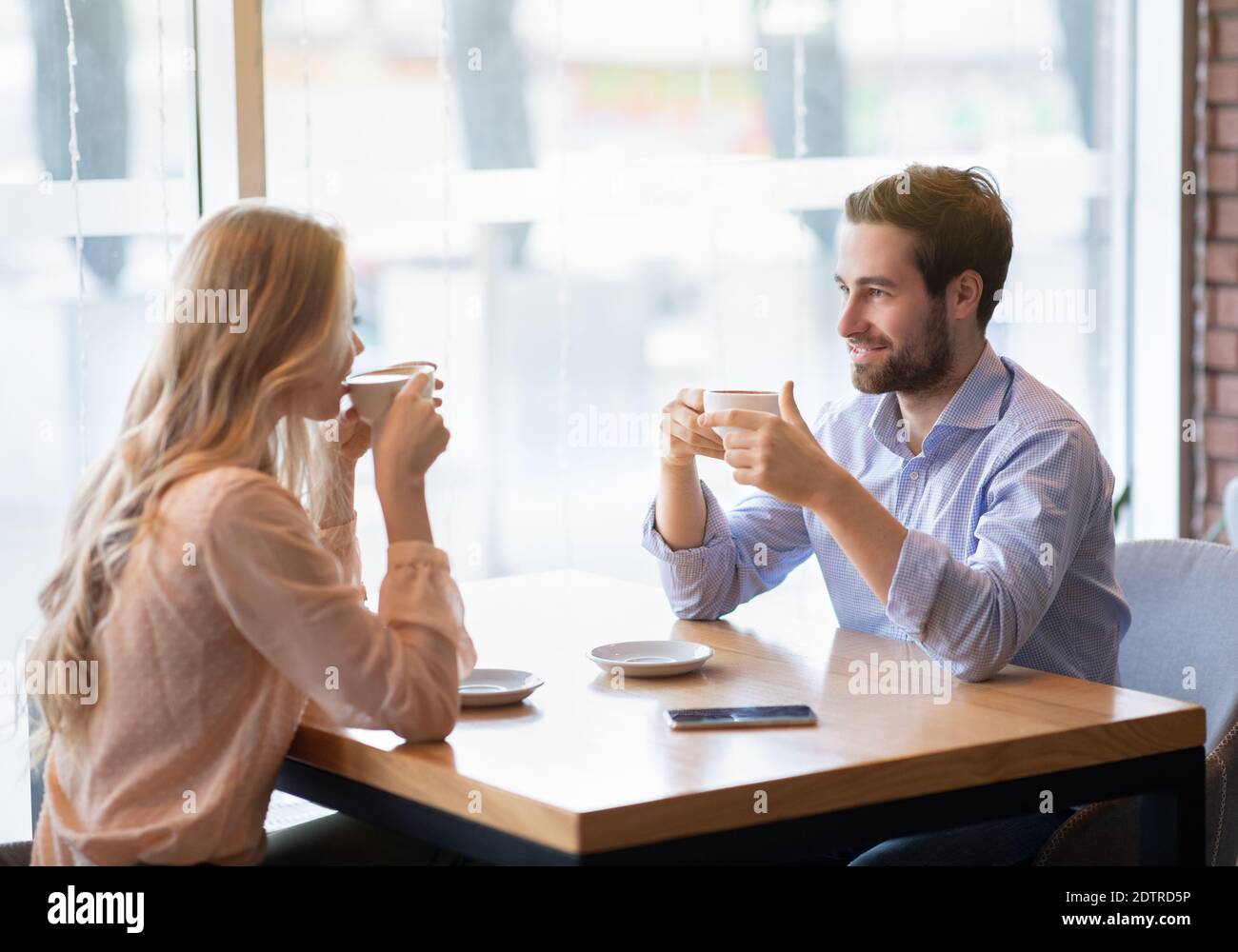 Portrait d'un couple romantique charmant assis dans un café urbain avec du café frais, appréciant leur date, ayant une discussion amicale Banque D'Images