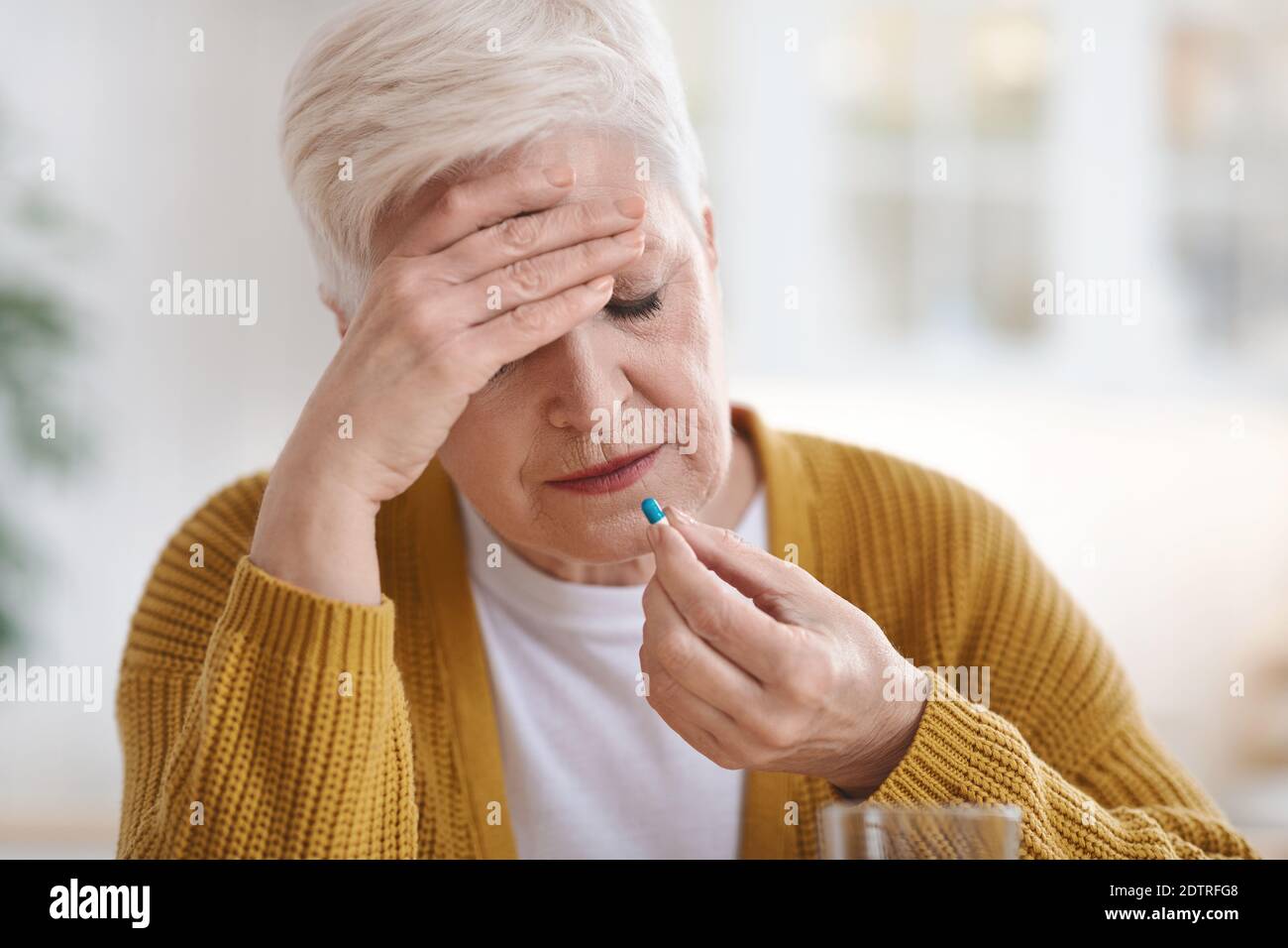 Femme âgée souffrant de maux de tête, prenant la pilule Banque D'Images