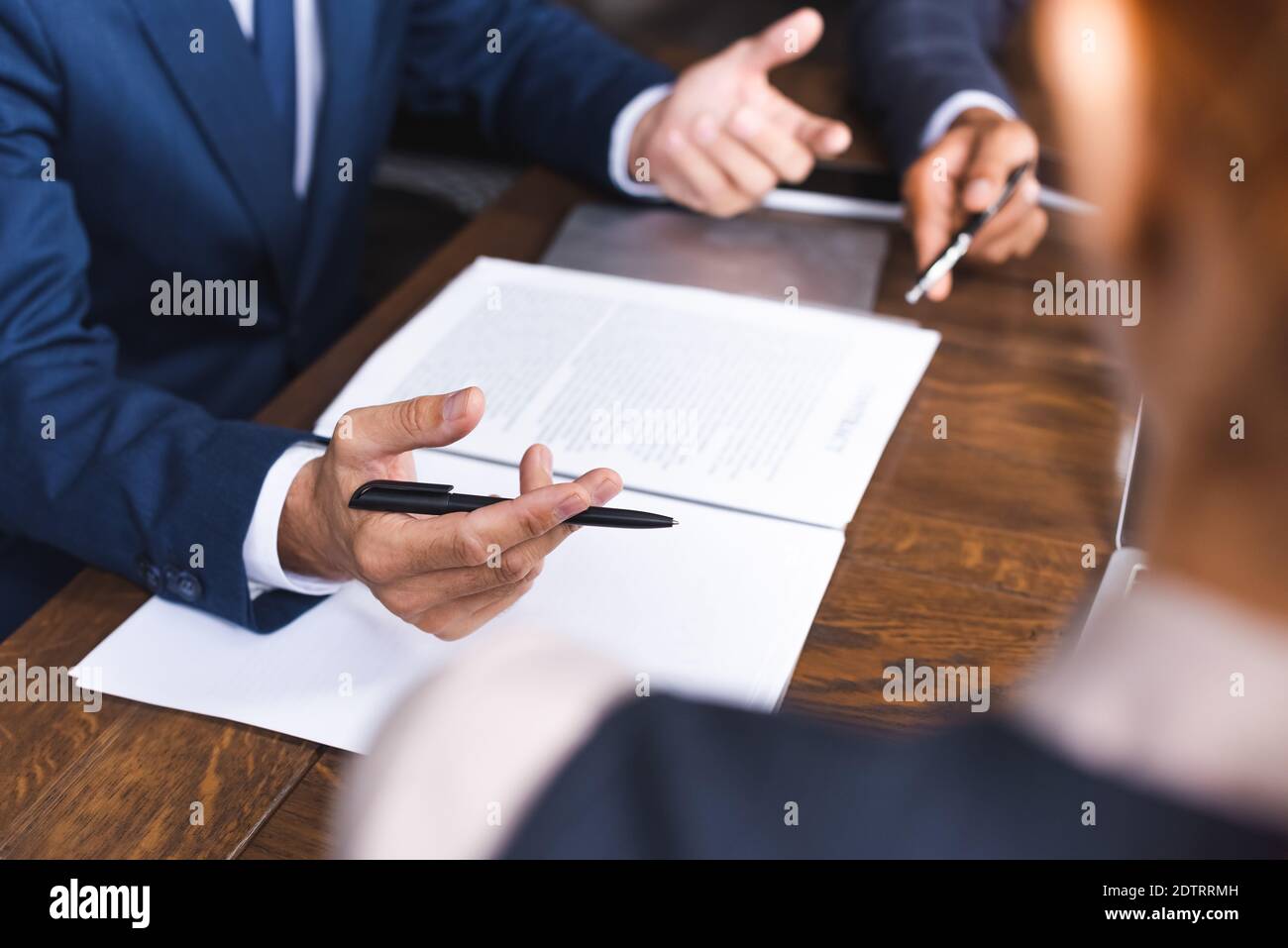 Vue rognée de l'investisseur avec le stylo gestante à proximité des documents sur lieu de travail sur un premier plan flou Banque D'Images
