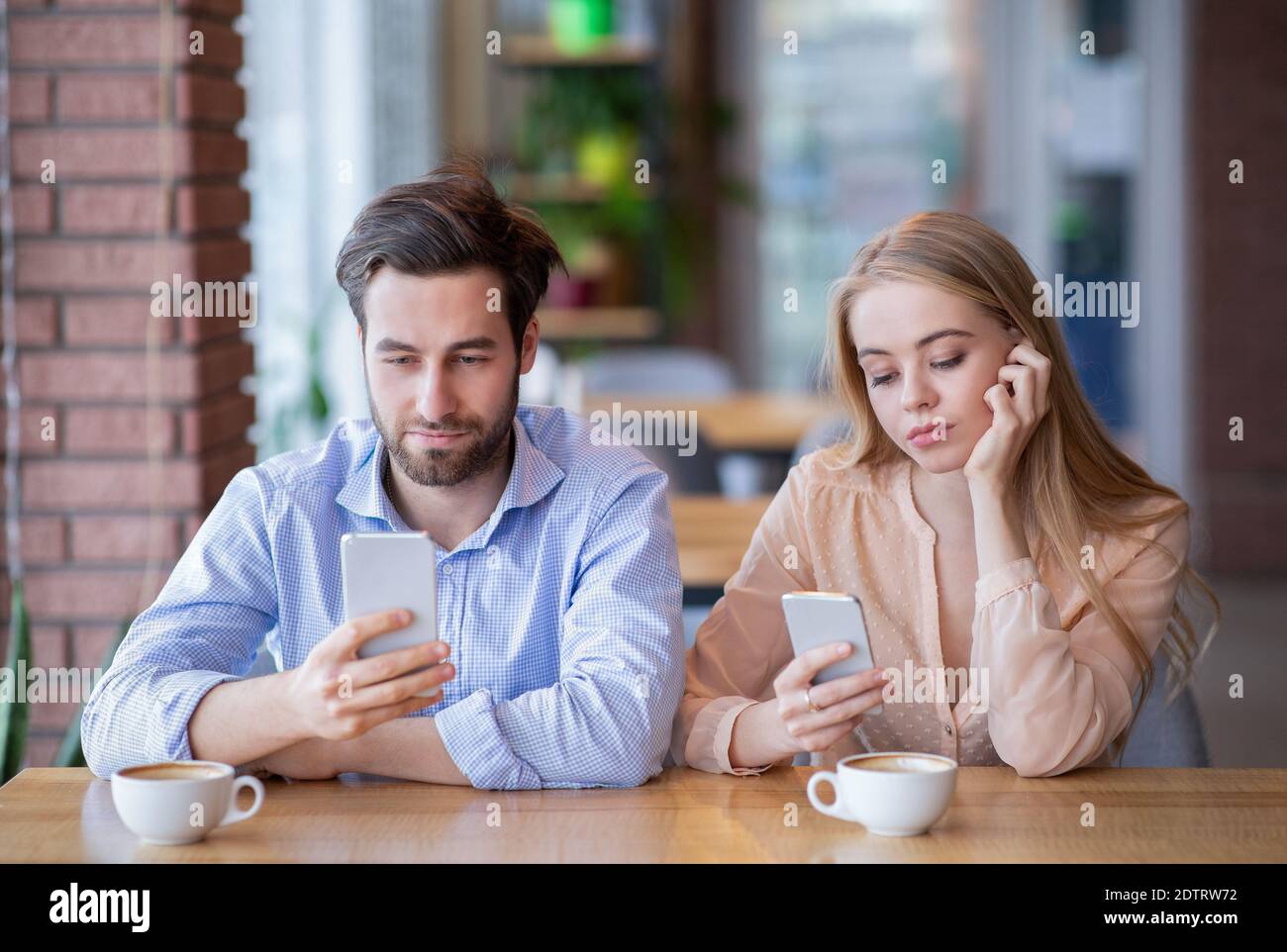 Addiction et concept de téléphone intelligent. Jeune couple sur une date ennuyeuse, coincé dans des gadgets, négligeant l'un l'autre au café Banque D'Images