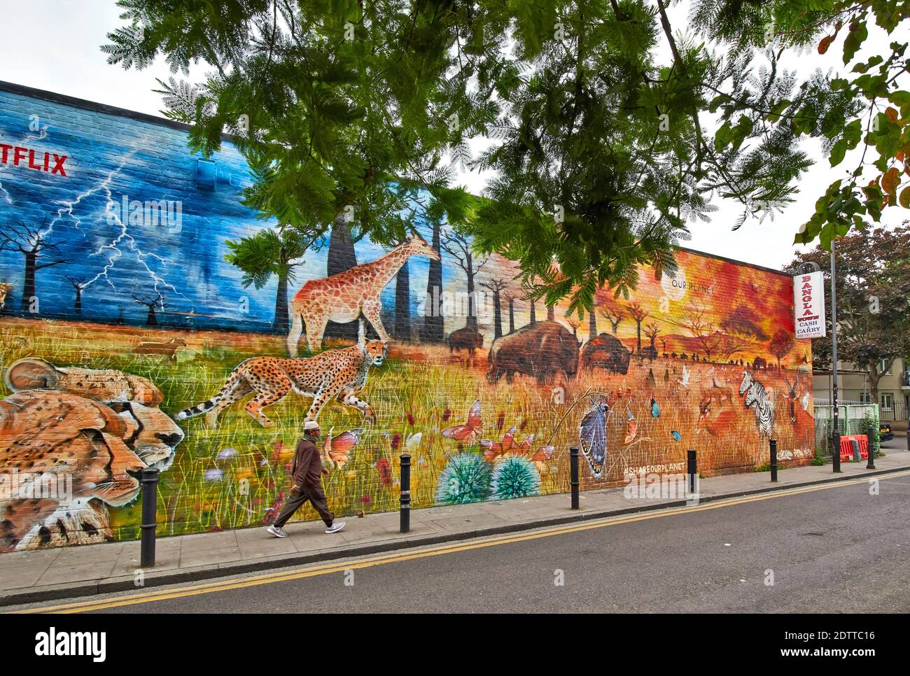 BRICK LANE SPITALFIELDS LONDRES SALON RUE AVEC ART sur un grand mur de briques et une marchette EN PASSANT PAR Banque D'Images