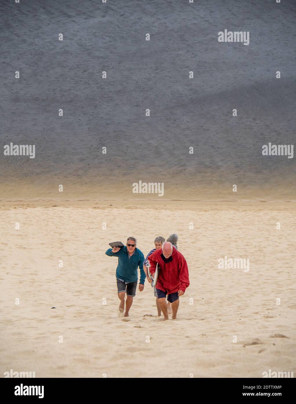 Des hommes grimpant sur une dune de sable pour faire du surf sur la rivière Moore Guilderton, en Australie occidentale. Banque D'Images