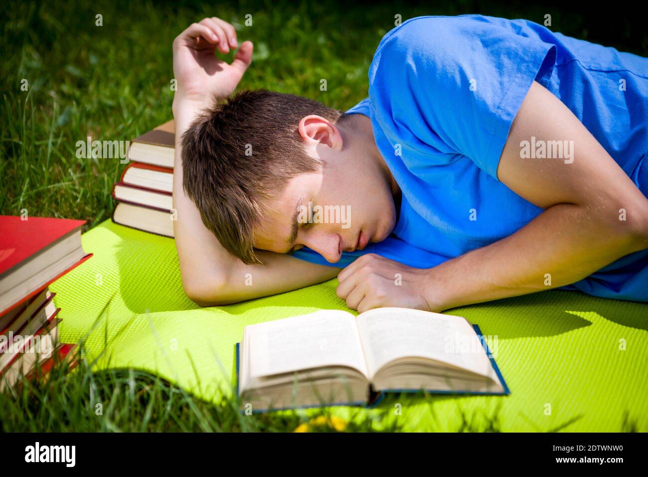 Un jeune homme dorment avec un livre sur la prairie d'été Banque D'Images