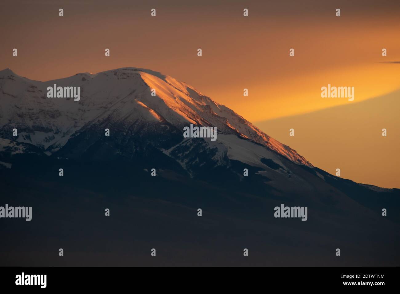 Silhouette de montagne enneigée au coucher du soleil contre le ciel orange et rose et les nuages Banque D'Images