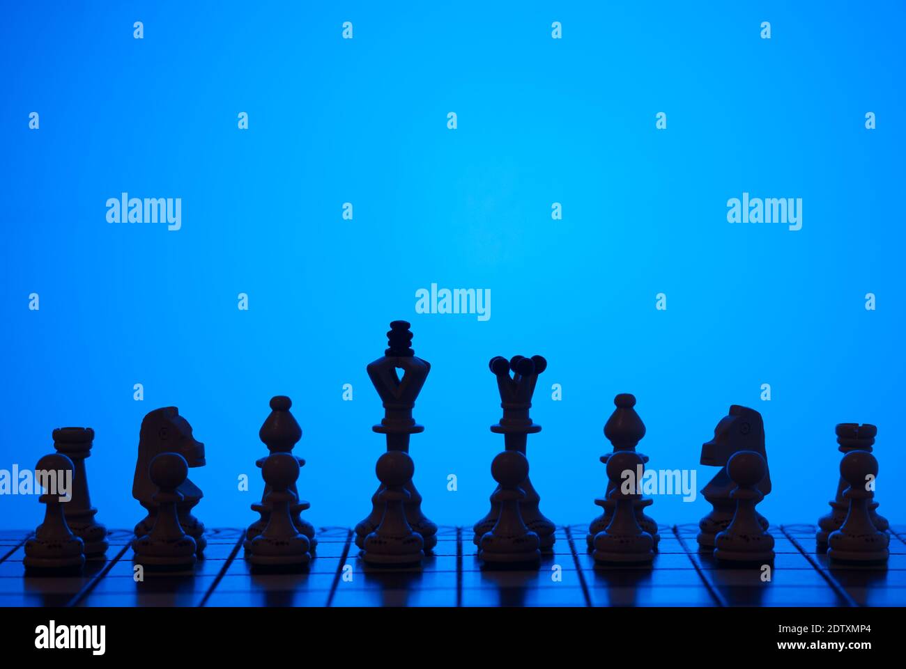 Arrière-plan créatif avec le plateau d'échecs et les figures d'échecs sur fond bleu foncé. Orientation horizontale. Banque D'Images