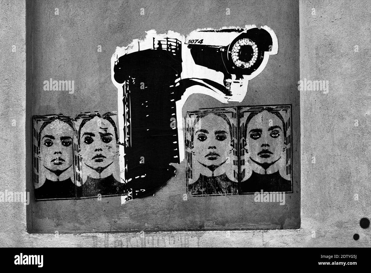 Des graffitis sont collés sur un mur représentant une caméra de surveillance et une femme. Image mono. Banque D'Images