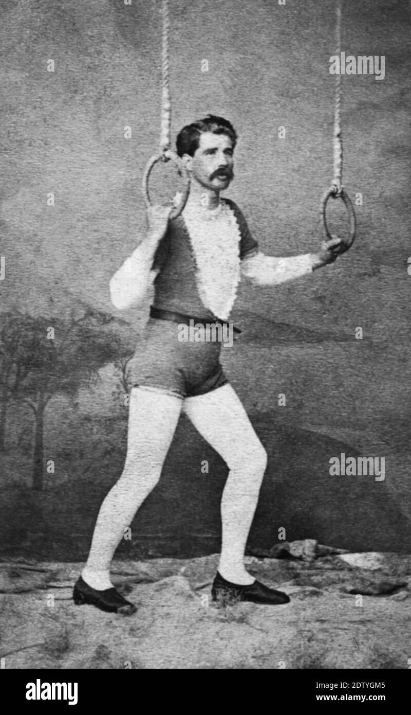 Ce c. 1872 homme était un cirque acrobat posant avec une paire d'anneaux suspendus du plafond. Dans les années 1870, les photographes ne pouvaient pas prendre de photos d'action en direct dans les cirques pendant les performances. Ainsi, tout artiste de cirque qui voulait des photos pour lui-même, ou pour vendre au public, a dû apporter son costume et son équipement au studio du photographe. Cet homme a probablement fait un certain nombre d'actes acrobatiques, mais être un aerialiste exécutant des anneaux suspendus a probablement été son meilleur et le plus dangereux acte. Pour voir mes autres images de cirque, recherchez: Prestor millésime cirque Banque D'Images