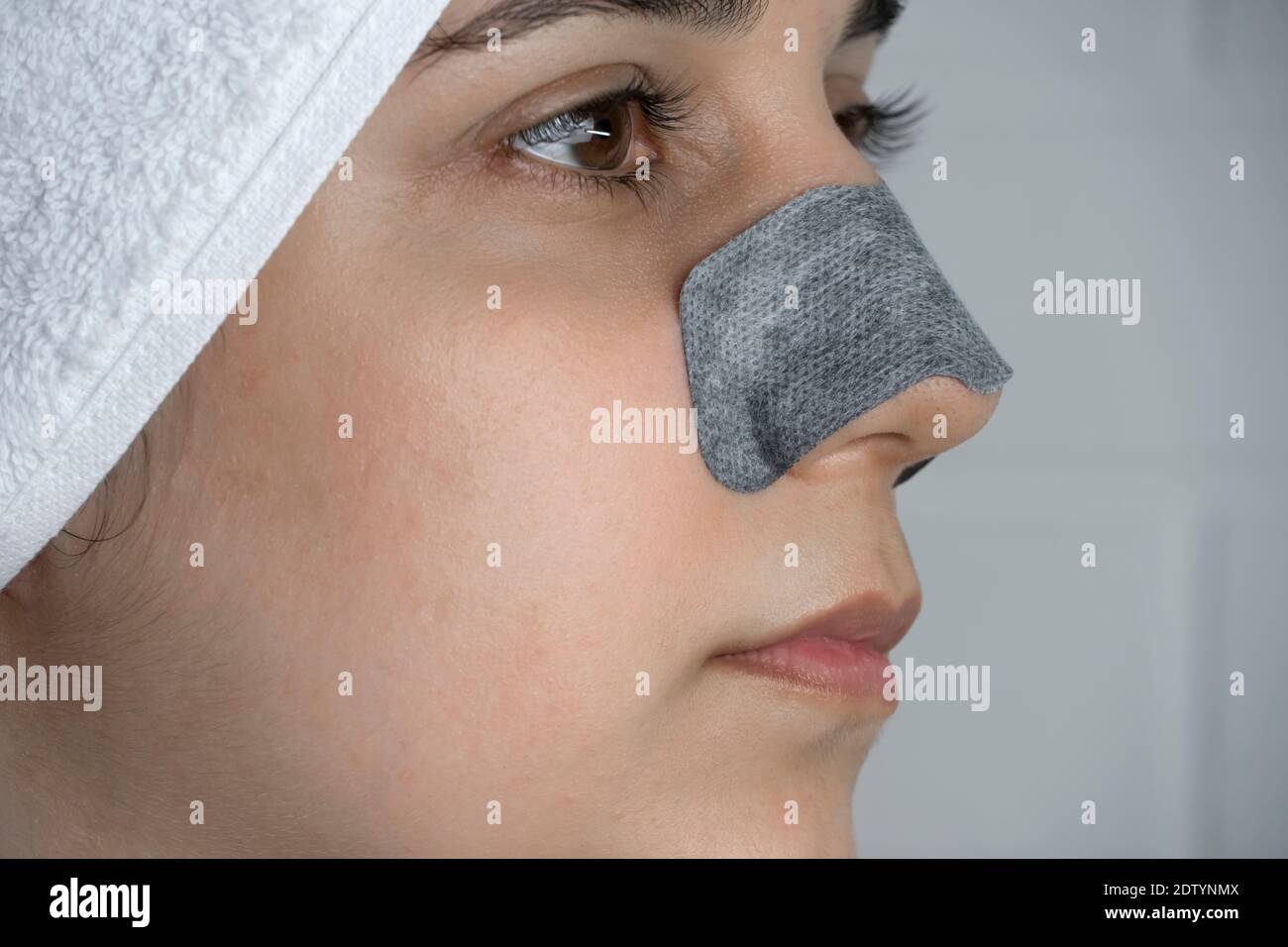 Une femme colle une bande de nettoyage sur son nez. Points noirs sur le nez.  Fille sans maquillage dans la salle de bains. Soins de la peau, problèmes  de peau, nettoyage. Naturel