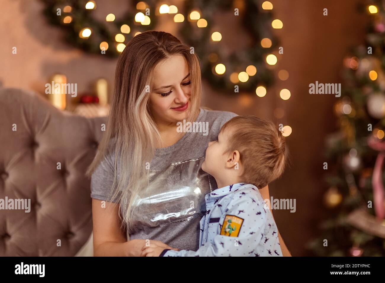 Une jeune fille et un garçon souriants s'assoient dans une salle de Noël décorée et apprécient les vacances et les cadeaux. Mise au point douce sélective. Côté. Le concept de l'hiver ho Banque D'Images