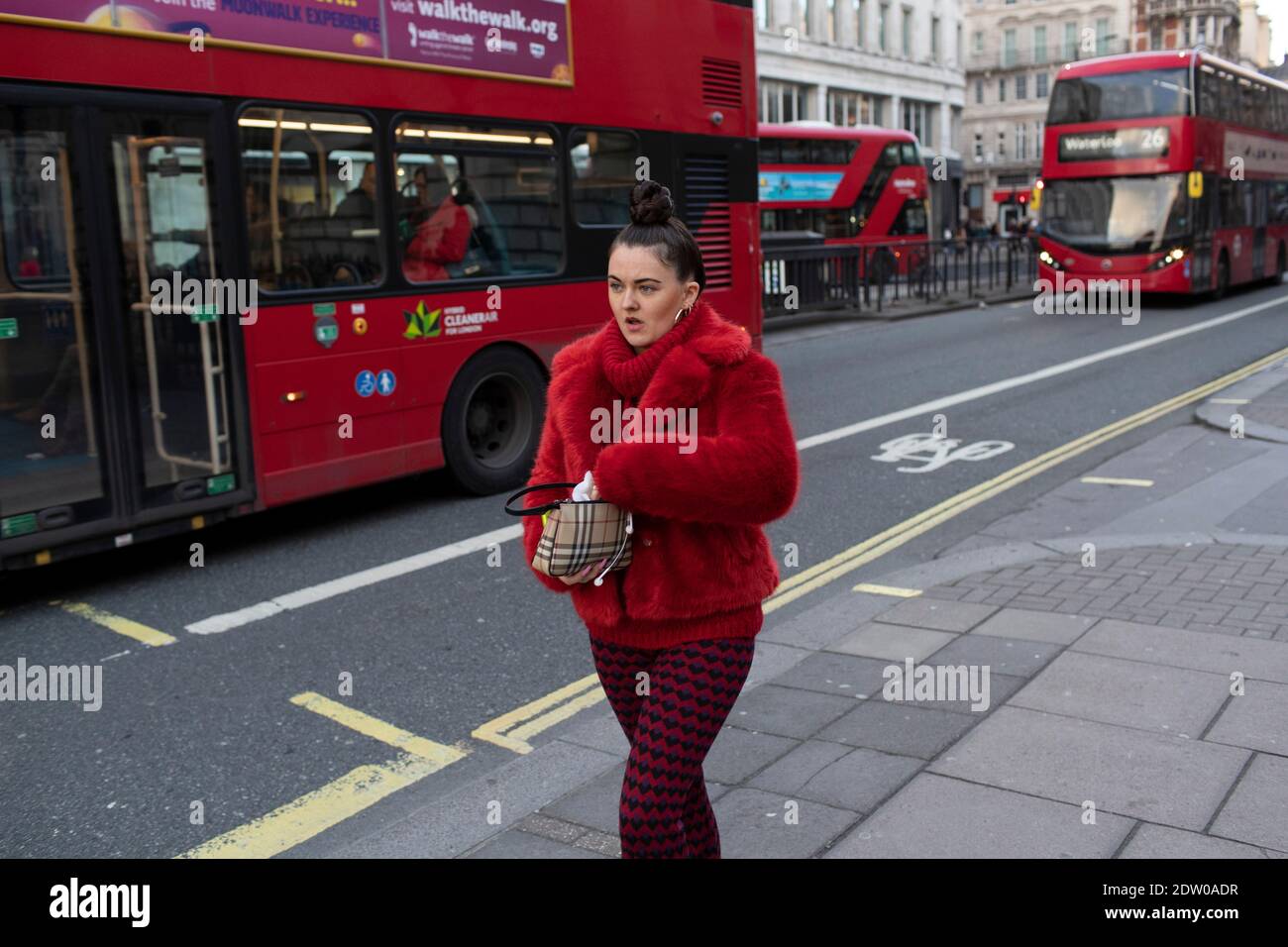 Une fille vêtue de rouge descend Oxford Street Banque D'Images
