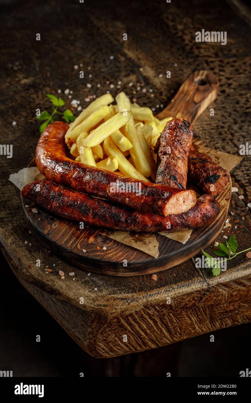 Concept de grill. Viande de porc savoureuse grillée, rôtie et frite avec frites sur l'ancienne planche à découper en bois. Banque D'Images