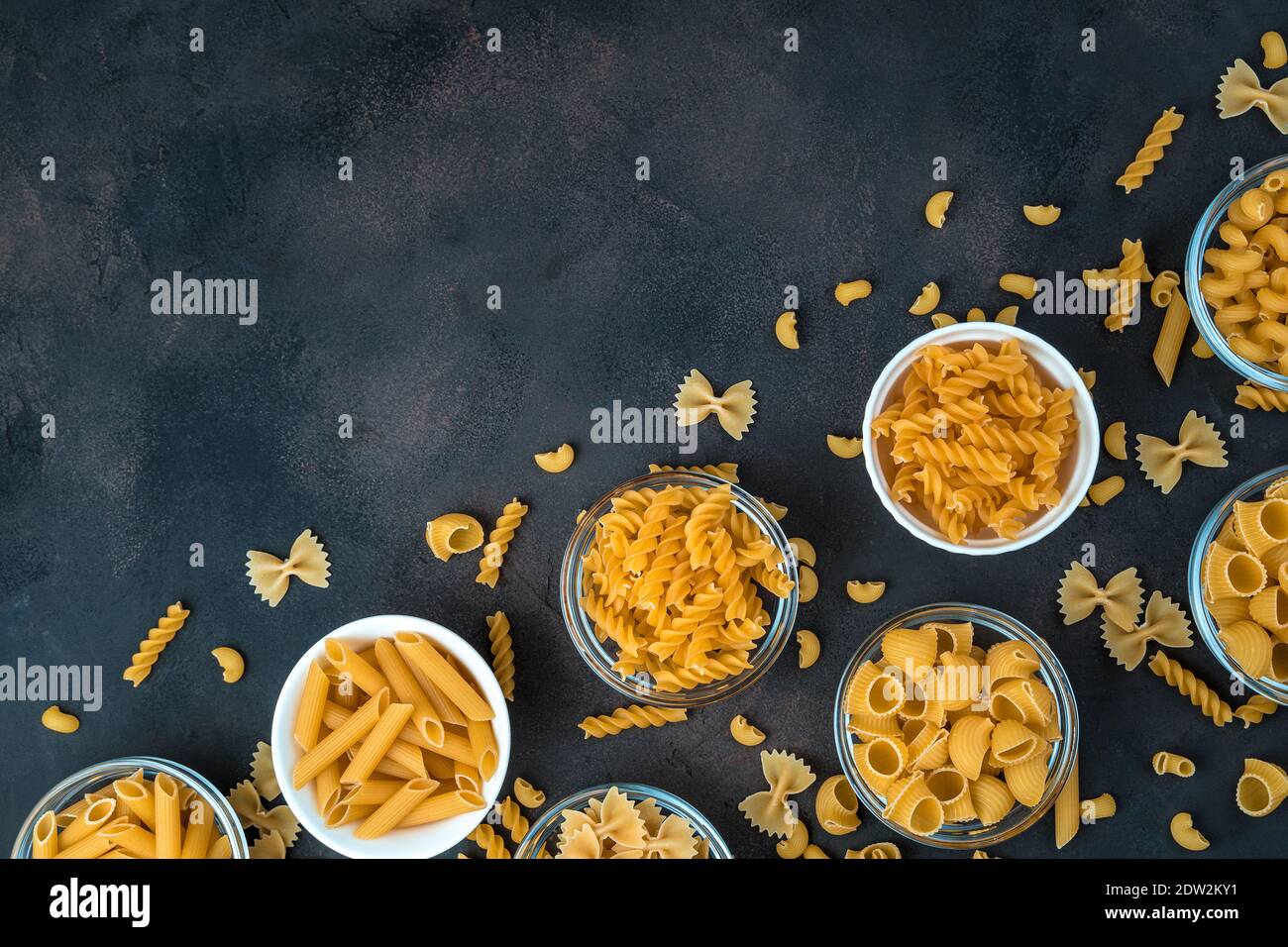 Pâtes de différents types dans des bols sur fond de béton foncé. Banque D'Images