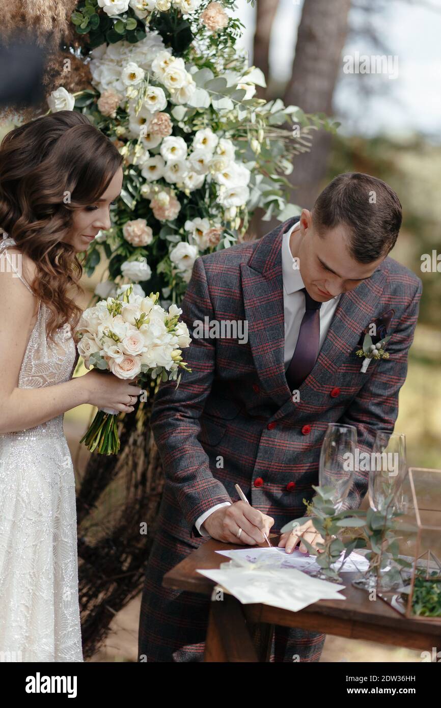 Marié signant des papiers de mariage et mariée le regardant à la cérémonie de mariage. Bonne nouvelle Banque D'Images