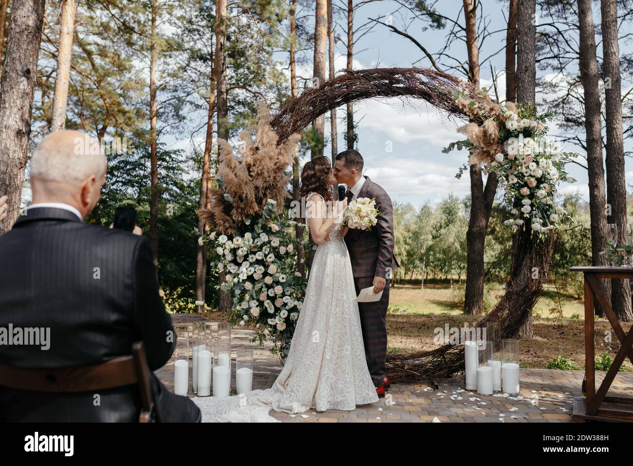 Homme prenant une photo de la mariée embrassante et du marié à la cérémonie de mariage. Heureux newlyweds à la cérémonie de mariage Banque D'Images