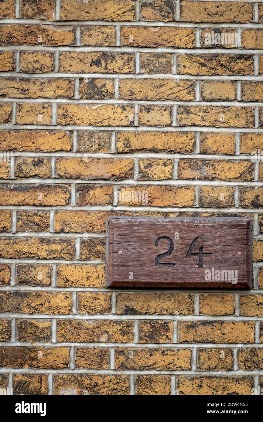 Une plaque en laine sur un mur de briques jaunes avec le numéro 24 Banque D'Images