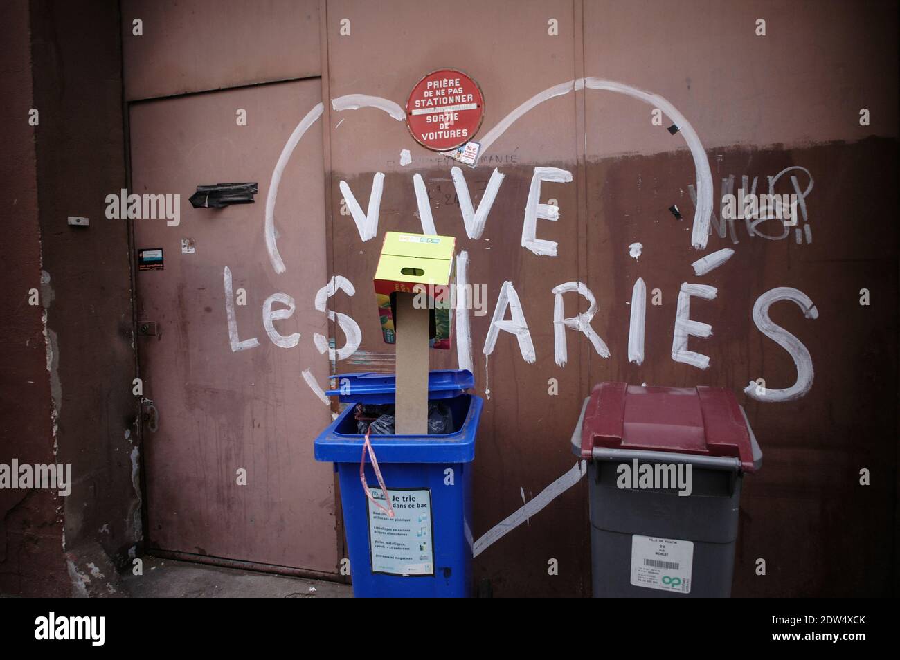 TEXTE « LONG LIVE THE NEWLYWEDS » PEINT SUR LE DEVANT D'UN PORTE DE GARAGE AVEC UN PANNEAU D'INTERDICTION DE STATIONNEMENT OÙ SE TROUVENT UN COUPLE DE POUBELLES - PARIS FRANCE - PHOTOGRAPHIE DE RUE - ARCHIVE COULEUR © F.BEAUMONT Banque D'Images
