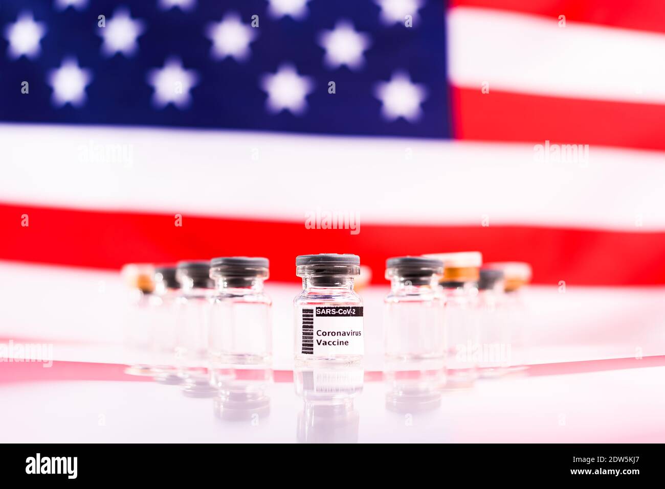Flacons médicaux avec le vaccin Covid et une seringue, devant un drapeau américain non focalisé. Banque D'Images
