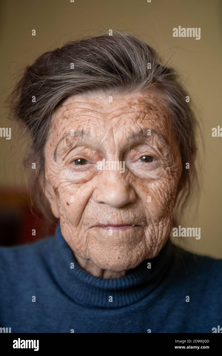90 ans mignonne femme âgée avec cheveux gris et rides visage, portant chandail, portrait grand, souriant et regardant joyeusement, arrière-plan de la pièce. TH Banque D'Images
