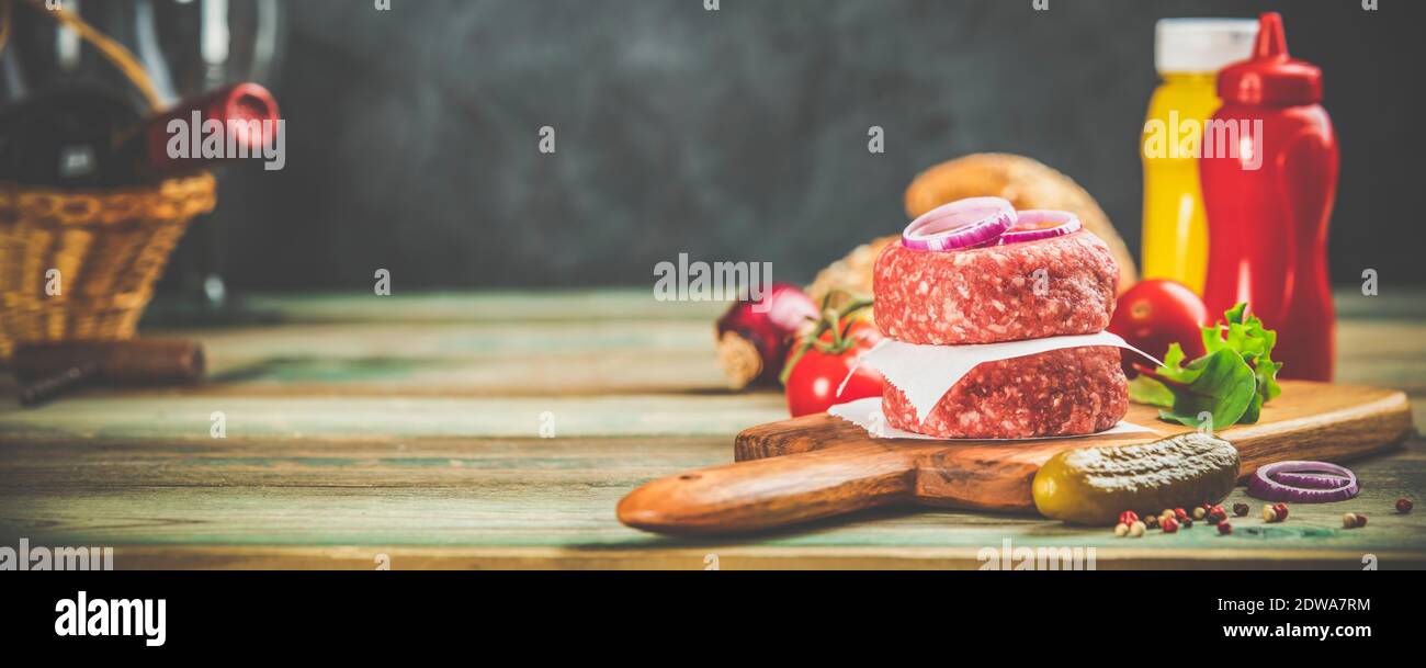 Les hamburgers faits maison. Galettes de b oe uf cru et de pain ciabatta avec d'autres ingrédients pour les hamburgers sur fond de bois Banque D'Images