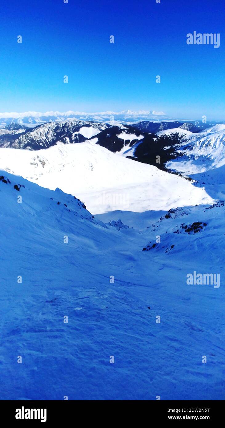 Vue panoramique des montagnes aux sommets enneigés contre Ciel Bleu clair Banque D'Images