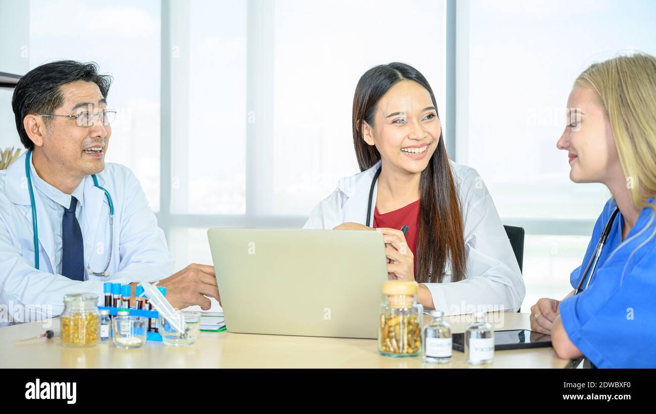 Groupe de médecins portant un manteau blanc formel et un costume de gommage bleu, réunion de travail d'équipe avec ordinateur portable à l'hôpital. spécialiste des soins de santé Banque D'Images