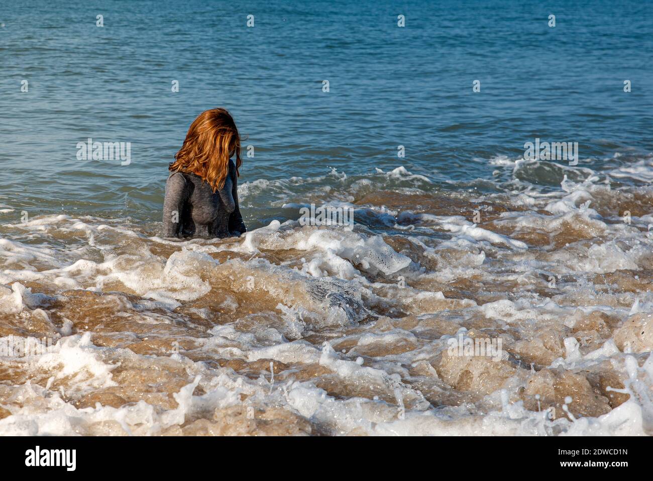 Femme sortant de la mer dans une robe humide après une baignade à la plage Banque D'Images