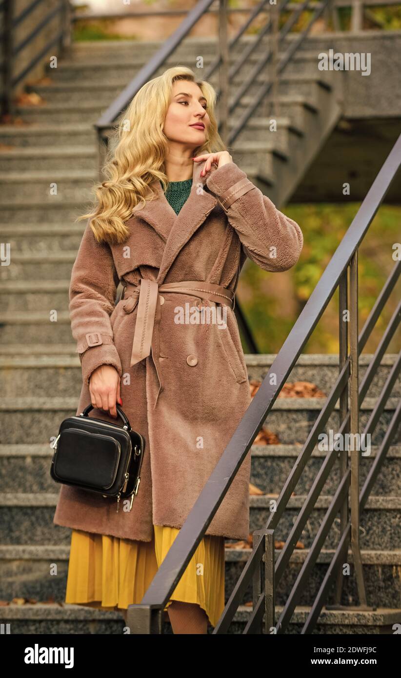 Fille dans un manteau chaud debout milieu urbain. Créez une tenue d'automne  confortable et jolie. Tenue d'automne. Femme porter une tenue élégante et  porte-monnaie. Vêtements de dessus en fourrure écologique moderne et