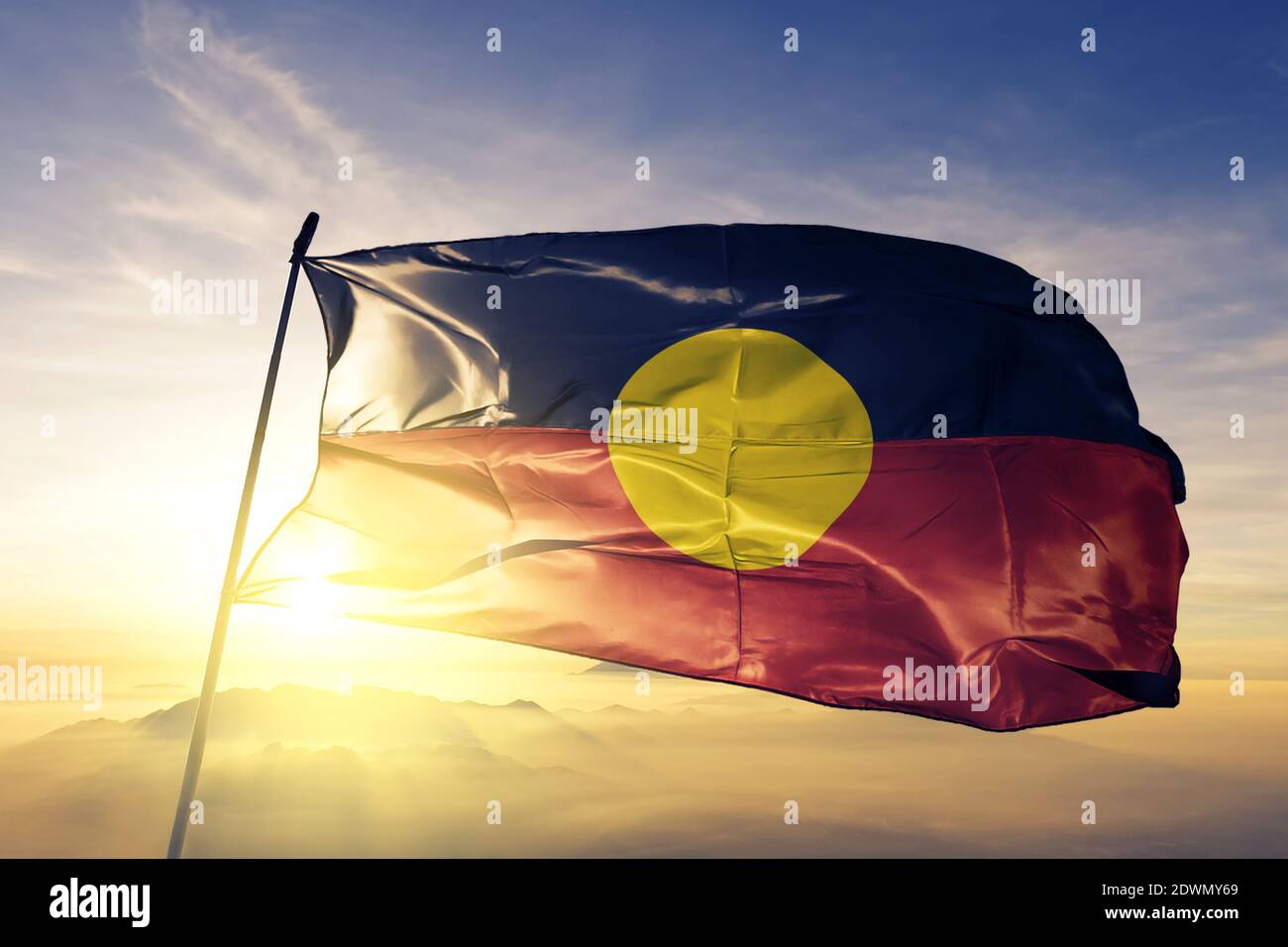 Drapeau aborigène australien qui agite sur le brouillard de lever du soleil Banque D'Images