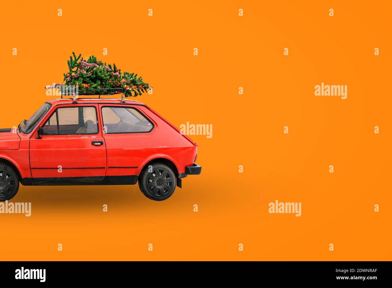 Voiture rétro rouge. Arbre de Noël sur le toit de la voiture. Livraison de marchandises, voyages du nouvel an et visites. Arrière-plan de Noël Banque D'Images