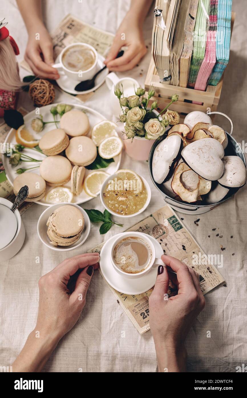 Les mains élégantes des femmes tiennent une tasse blanche avec du cappuccino. La cuisine est encore une vie dans le style français. Virage. Tir vertical. Vue de dessus Banque D'Images