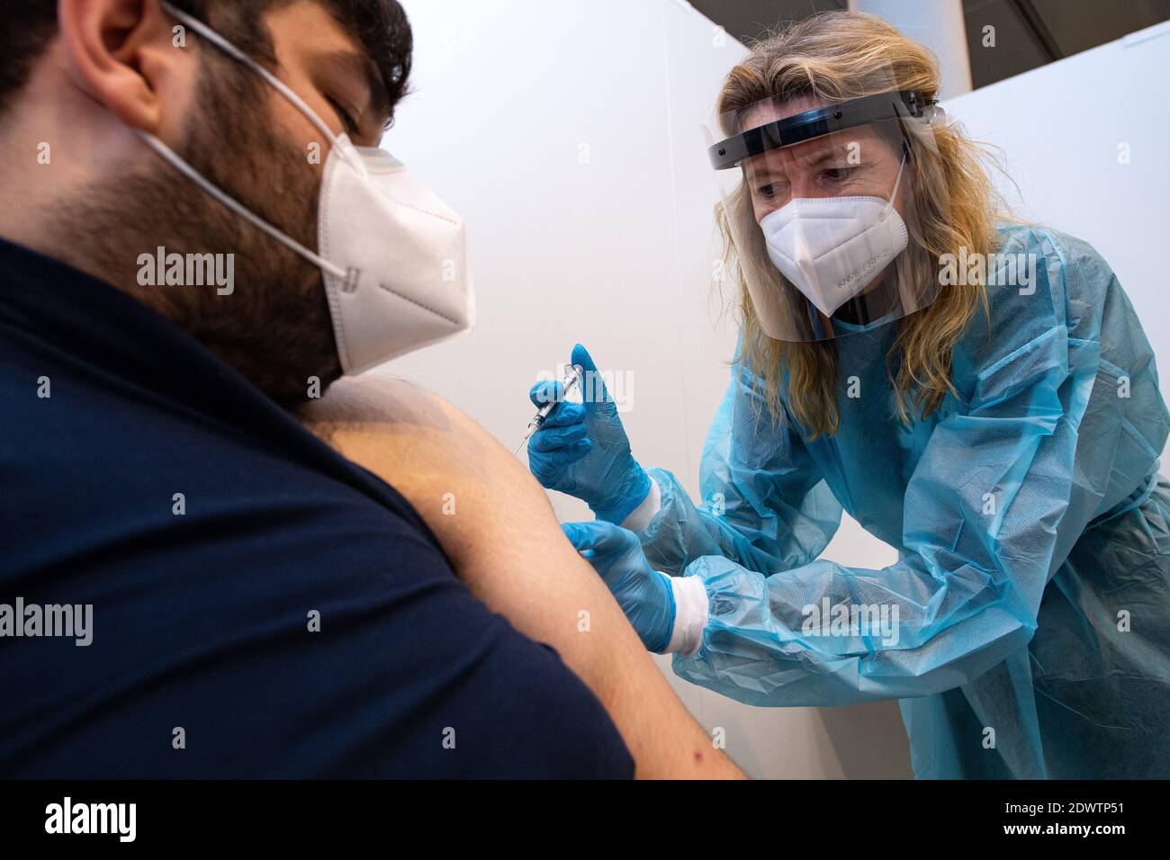 Greven, Allemagne. 23 décembre 2020. Anja Büscher (r), assistante médicale de l'Association des médecins légaux d'assurance maladie, place une seringue sur le bras de Leon Berisa de l'Agence fédérale allemande de secours technique (THW) dans le centre de vaccination du district de Steinfurt à des fins de test. Un essai a commencé à l'aéroport au centre de vaccination avec environ 50 personnes de test de THW, DLRG, Malteser, DRK Kreisverband ST et DRK Kreisverband TE. Credit: Guido Kirchner/dpa/Alay Live News Banque D'Images