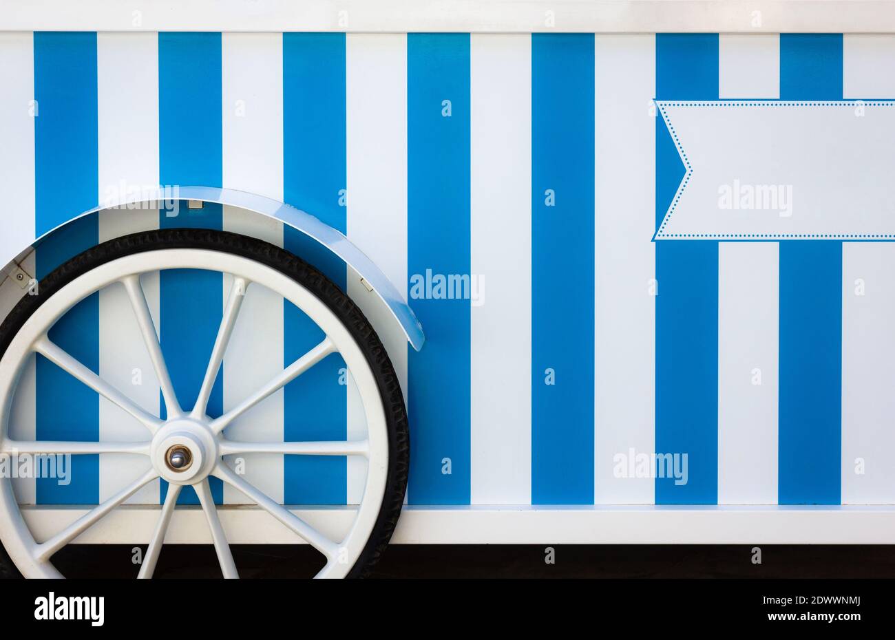 Roue de chariot de glace vintage à rayures bleues et blanches. Camion du fournisseur de rue, véhicule commercial servant de point de vente au détail mobile Banque D'Images
