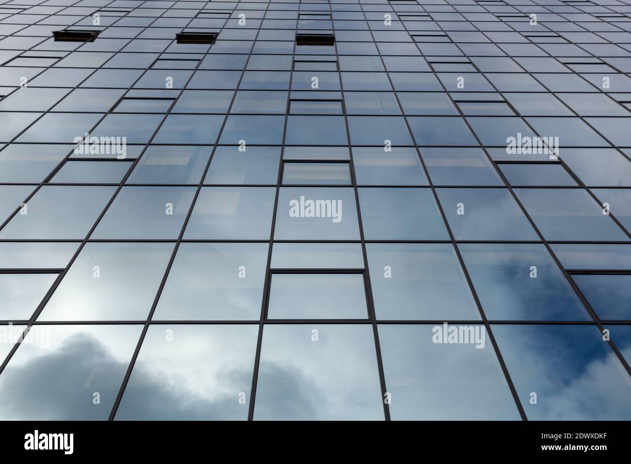 Vue sur les fenêtres en verre d'un immeuble de bureau qui sont tous fermés sauf trois Banque D'Images