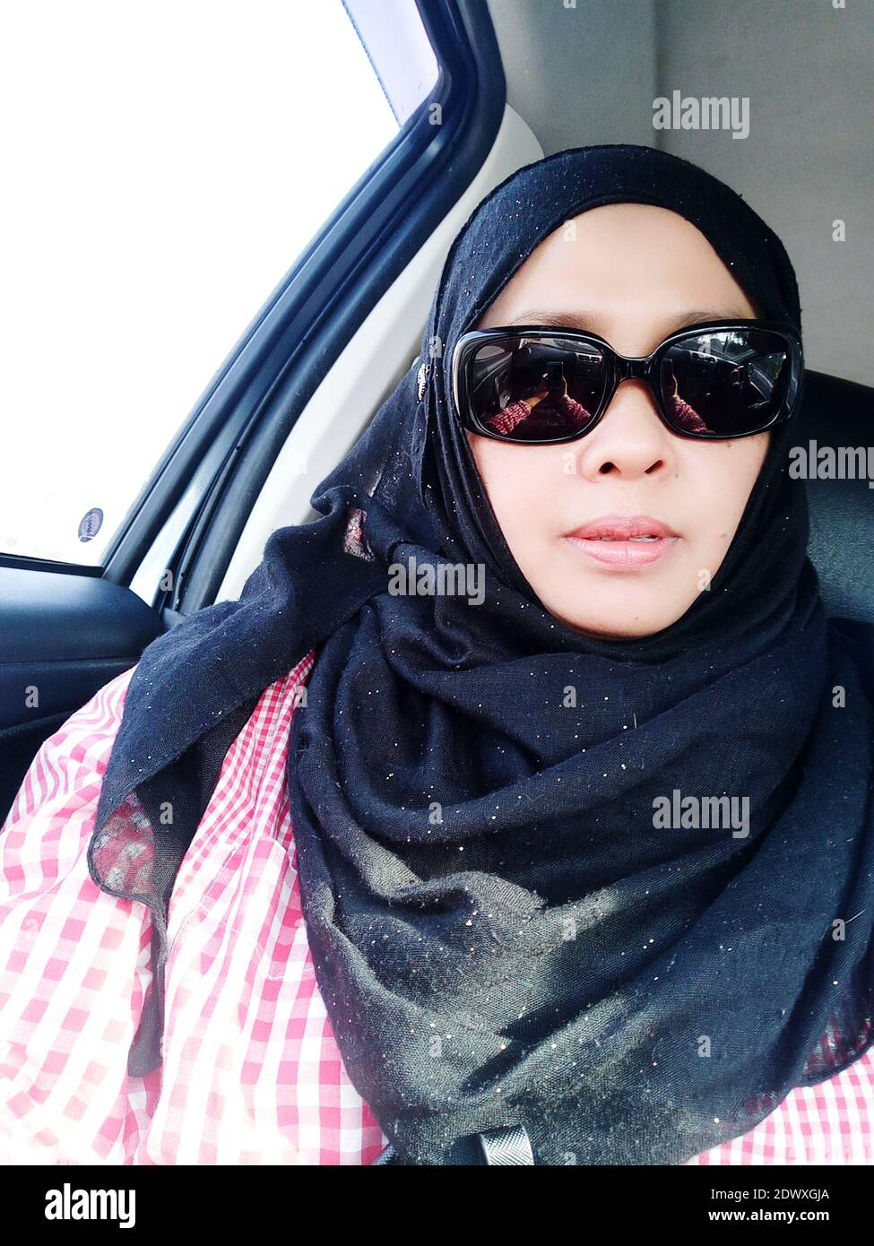 Portrait d'une femme portant des lunettes de soleil et hijab en voiture  Photo Stock - Alamy